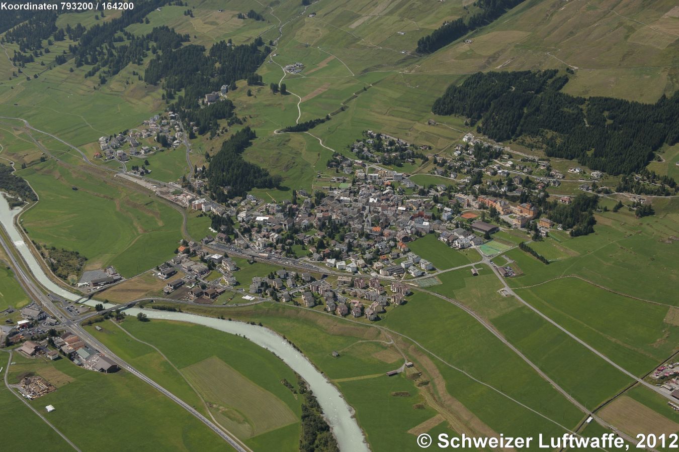 Zuoz (Position: 2'793'201.01, 1'164'268.65). Vor der Brücke (links unten): Ortsteil Resgia; Siedlung links oben: Chaunt da Cusch. - Die Gemeinde Zuoz ist bekannt für das 'Lyceum Alpinum', ein Internat für 11 bis 20-Jährige. (roter Gebäudekomplex Bildmitte rechts).